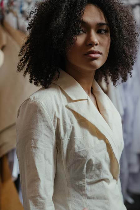 Black womxn with a professional 3C afro hairstyle wearing a linen shirt looking to the side